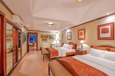 a hotel room with two beds and a living room at Hotel Casa Roland San Jose in San José