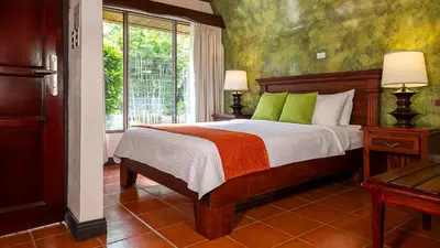 a bedroom with a bed with green pillows and a window at Tilajari Hotel Resort in Fortuna