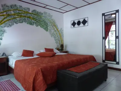 a bedroom with a large bed with a red bedspread at Hotel Villa Romantica in Manuel Antonio