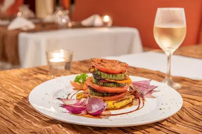a plate of food on a table with a glass of wine at Hotel Villas Lirio in Manuel Antonio