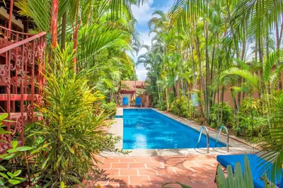 a swimming pool in a garden with palm trees at Hotel Villas Lirio in Manuel Antonio