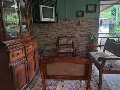 a living room with chairs and a tv on a wall at Hospedaje Luis & Ana in Pejibaye