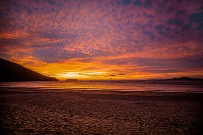 a sunset on a beach with the ocean at Hotel Bosque del Mar Playa Hermosa in Playa Hermosa