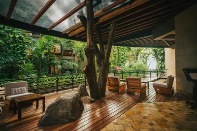 a living room with a large rock and wooden floors at Hotel Bosque del Mar Playa Hermosa in Playa Hermosa