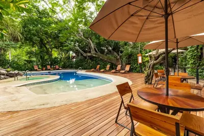 a deck with a pool and a table with an umbrella at Hotel Bosque del Mar Playa Hermosa in Playa Hermosa