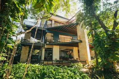 a house with a balcony in the middle of trees at Hotel Bosque del Mar Playa Hermosa in Playa Hermosa