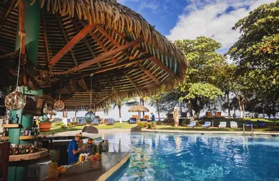 a man sitting at a bar next to a swimming pool at Bahia del Sol Beach front Boutique Hotel in Potrero