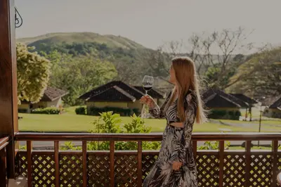 a woman standing on a balcony holding a glass of wine at Borinquen Thermal Resort in Liberia