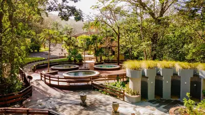 a garden with three pools and a fence at Borinquen Thermal Resort in Liberia