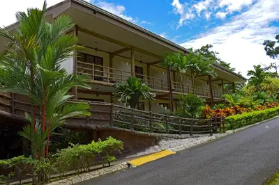 a building with palm trees next to a street at Hotel Los Lagos Spa & Resort in Fortuna