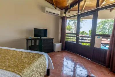 a bedroom with a bed and a television and a balcony at Hotel Terraza del Pacifico in Jacó