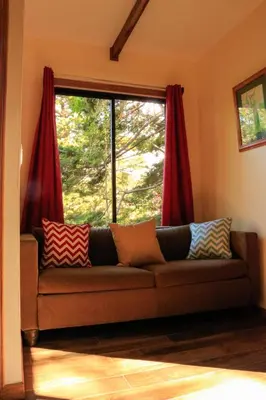 a couch in front of a window with red curtains at Moon Forest Apartments in Monteverde Costa Rica