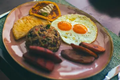 a plate of breakfast food with eggs sausage and toast at Amor Arenal Adults Friendly in Fortuna