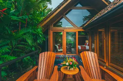 a porch with two chairs and a table with flowers at Amor Arenal Adults Friendly in Fortuna