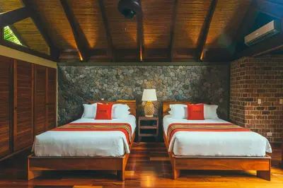 a bedroom with two beds and a brick wall at Amor Arenal Adults Friendly in Fortuna