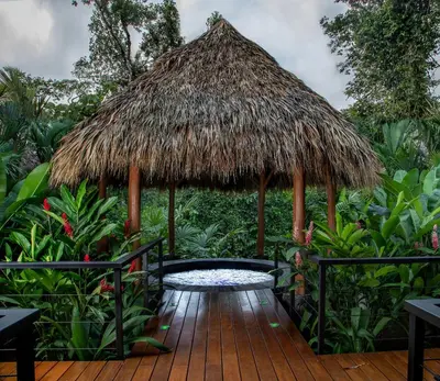 a hut with a wooden deck with a water fountain at Amor Arenal Adults Friendly in Fortuna