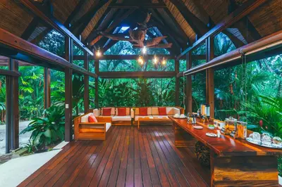 a conservatory with a table and chairs in a forest at Amor Arenal Adults Friendly in Fortuna