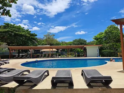 a swimming pool with lounge chairs and a pavilion at Nacazcol Hotel y Villas in Coco