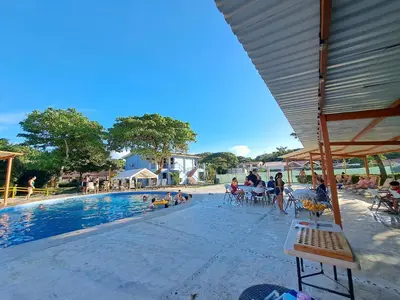 a group of people sitting around a swimming pool at Nacazcol Hotel y Villas in Coco