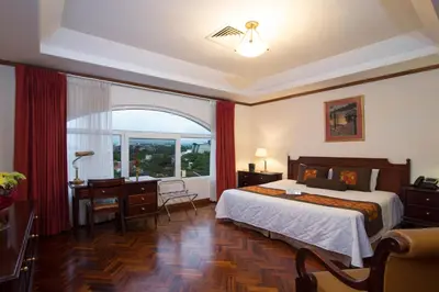 a bedroom with a bed and a desk and a window at Apartotel & Suites Villas del Rio in San José