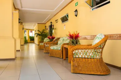 a hallway with wicker chairs and tables in a building at Apartotel & Suites Villas del Rio in San José
