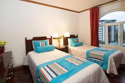 a hotel room with two beds and a window at Apartotel & Suites Villas del Rio in San José