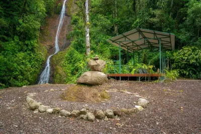 a rock statue in front of a waterfall at Hotel Quelitales in Cachí