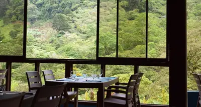 a table and chairs in a room with a large window at Hotel Quelitales in Cachí