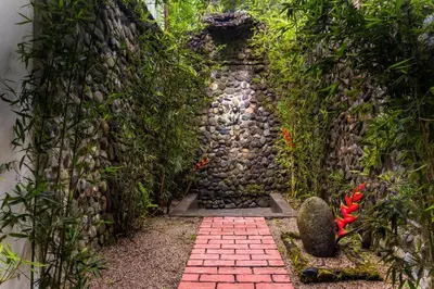a stone path in a garden with a stone wall at Hotel Quelitales in Cachí