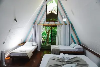 a room with three beds and a window at Calala Lodge in Cabuya