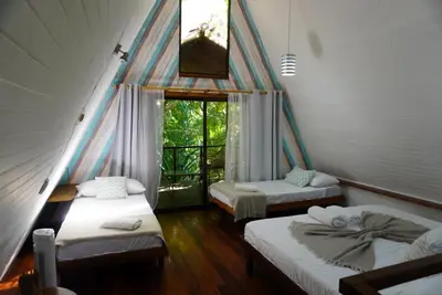 a room with three beds and a window at Calala Lodge in Cabuya