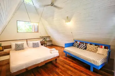 a room with two beds and a couch in a attic at Calala Lodge in Cabuya