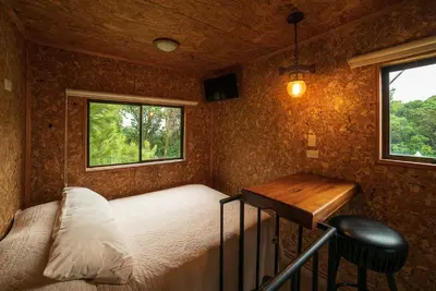 a bedroom with a bed and a desk and a window at Altura Hotel in Poasito