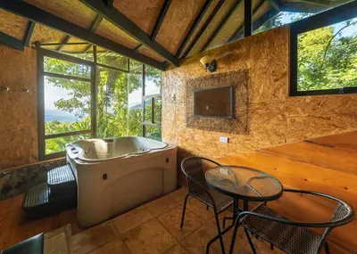 a bathroom with a tub and a table and chairs at Altura Hotel in Poasito