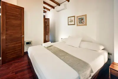 a bedroom with a bed with white sheets and a wooden door at Casas Santa Teresa in Santa Teresa Beach