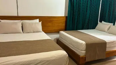two beds in a hotel room with green curtains at Hotel Javy in Liberia