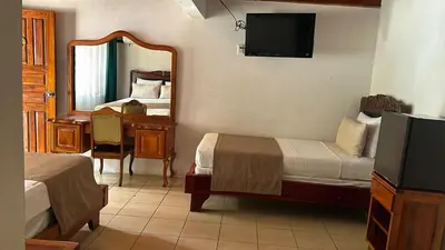 a bedroom with two beds and a mirror and a desk at Hotel Javy in Liberia