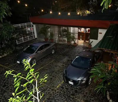 two cars parked in front of a garage at night at Hotel Javy in Liberia