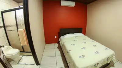 a small bedroom with a bed and a toilet at Arenal Red in Fortuna