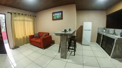 a kitchen with a table and a chair and a refrigerator at Arenal Red in Fortuna