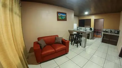a living room with a red chair and a kitchen at Arenal Red in Fortuna