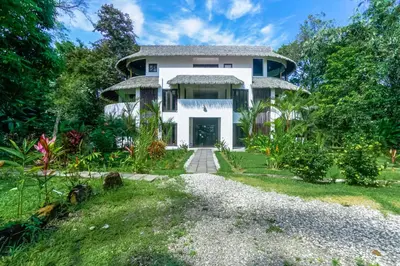 a large white house with a yard at Makara Rio Suite / Ground Floor in Uvita