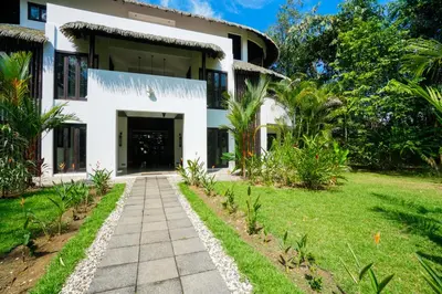 a white house with a walkway in front of it at Makara Mono Suite / 2nd Floor in Uvita