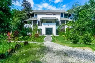 a large white house with a driveway at Makara Mono Suite / 2nd Floor in Uvita