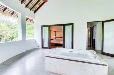a large white room with a bath tub and a bedroom at Makara Suite Penthouse in Uvita