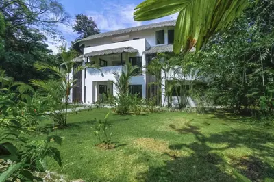 an exterior view of a white house with a yard at Makara Suite Penthouse in Uvita