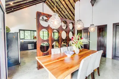 a dining room with a wooden table and white chairs at Makara Suite Penthouse in Uvita