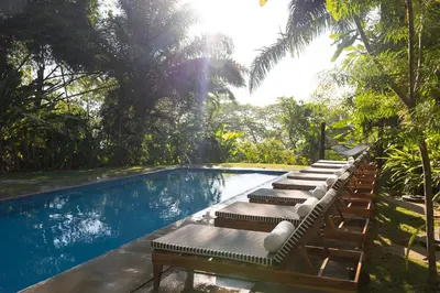 a row of lounge chairs next to a swimming pool at Hotel Nya in Montezuma