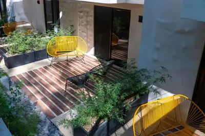 a patio with yellow chairs and tables and plants at Hotel Nya in Montezuma