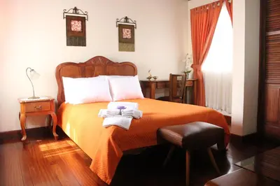 a bedroom with a bed with orange sheets and white pillows at Casa Mora B&B in Cartago